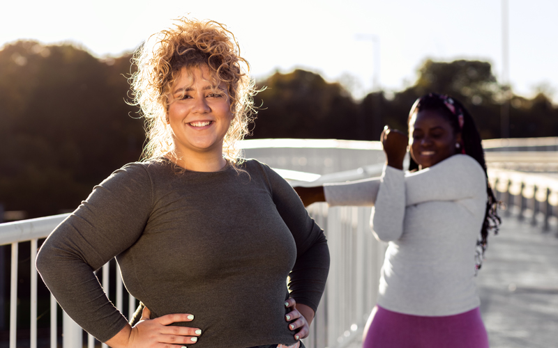 Eine übergewichtige Frau in Trainingskleidung, die zuvor Depressionen hatte, und eine normalgewichtige Frau sind fröhlich mit einem Workout beschäftigt.